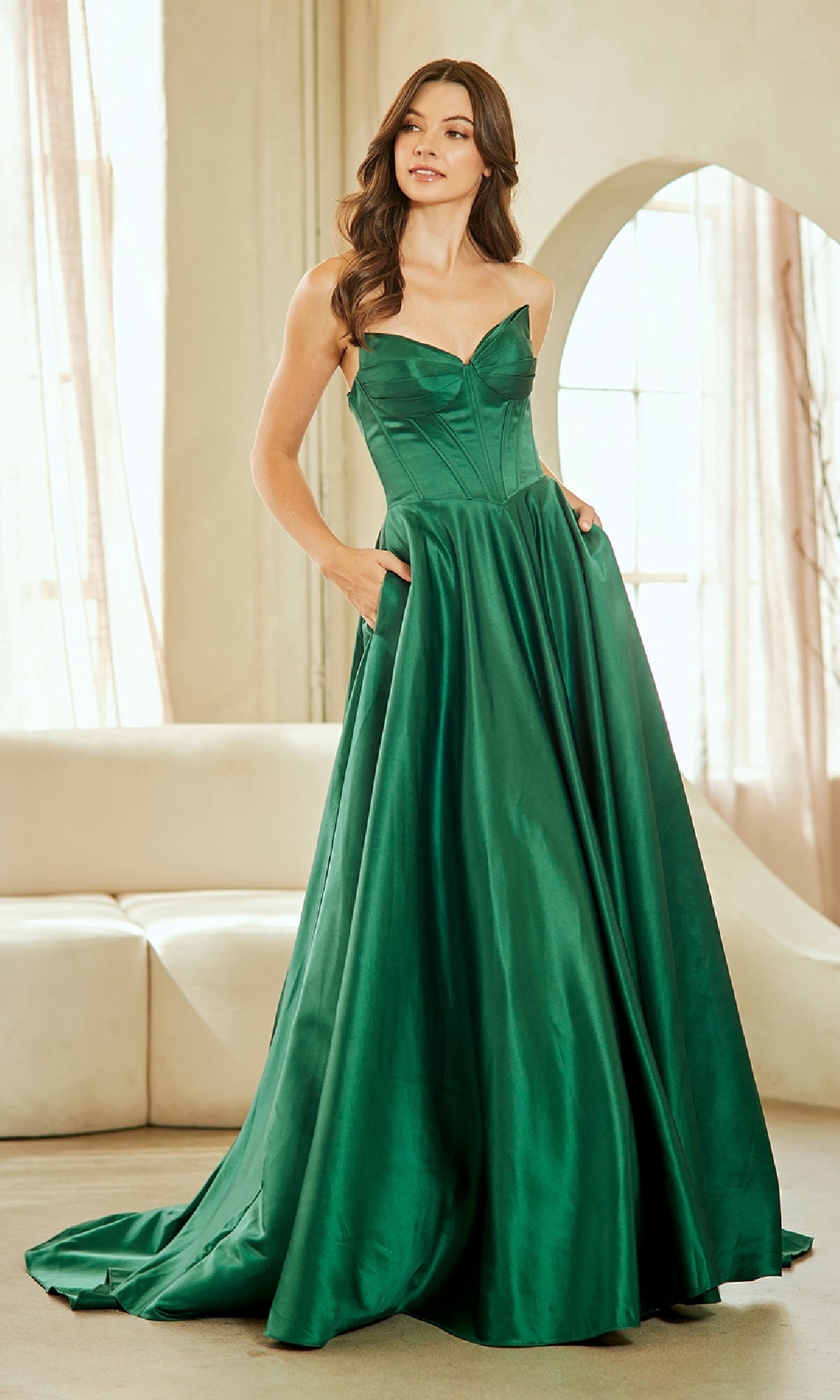Woman wearing an emerald green evening gown in a well-lit room.